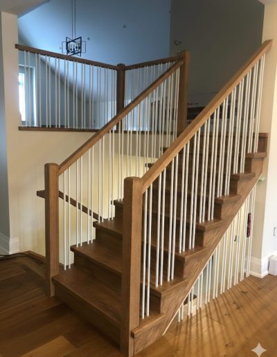 Stained oak staircase with elegant white spindles and natural wood handrails, custom-built for a home in Wasaga Beach, Ontario.