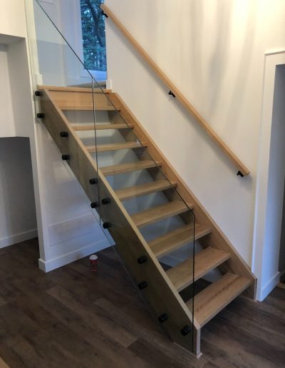Luxury modern floating wood staircase with glass railing in a Simcoe County home