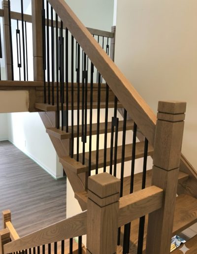 Custom oak staircase with modern black rectangular spindles and light gray hardwood floors in a Wasaga Beach home.