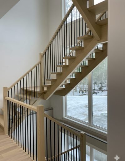 Custom modern oak staircase with black metal spindles and natural wood handrails in a Wasaga Beach home.