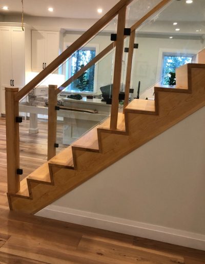 Modern wood staircase with glass railing and solid wood posts in Simcoe County