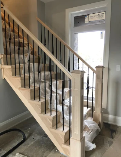 Custom natural wood staircase with black metal balusters installed in a Wasaga Beach home