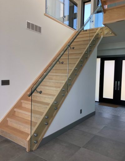 Modern wood staircase with glass railing and solid wood stringers in a Simcoe County home